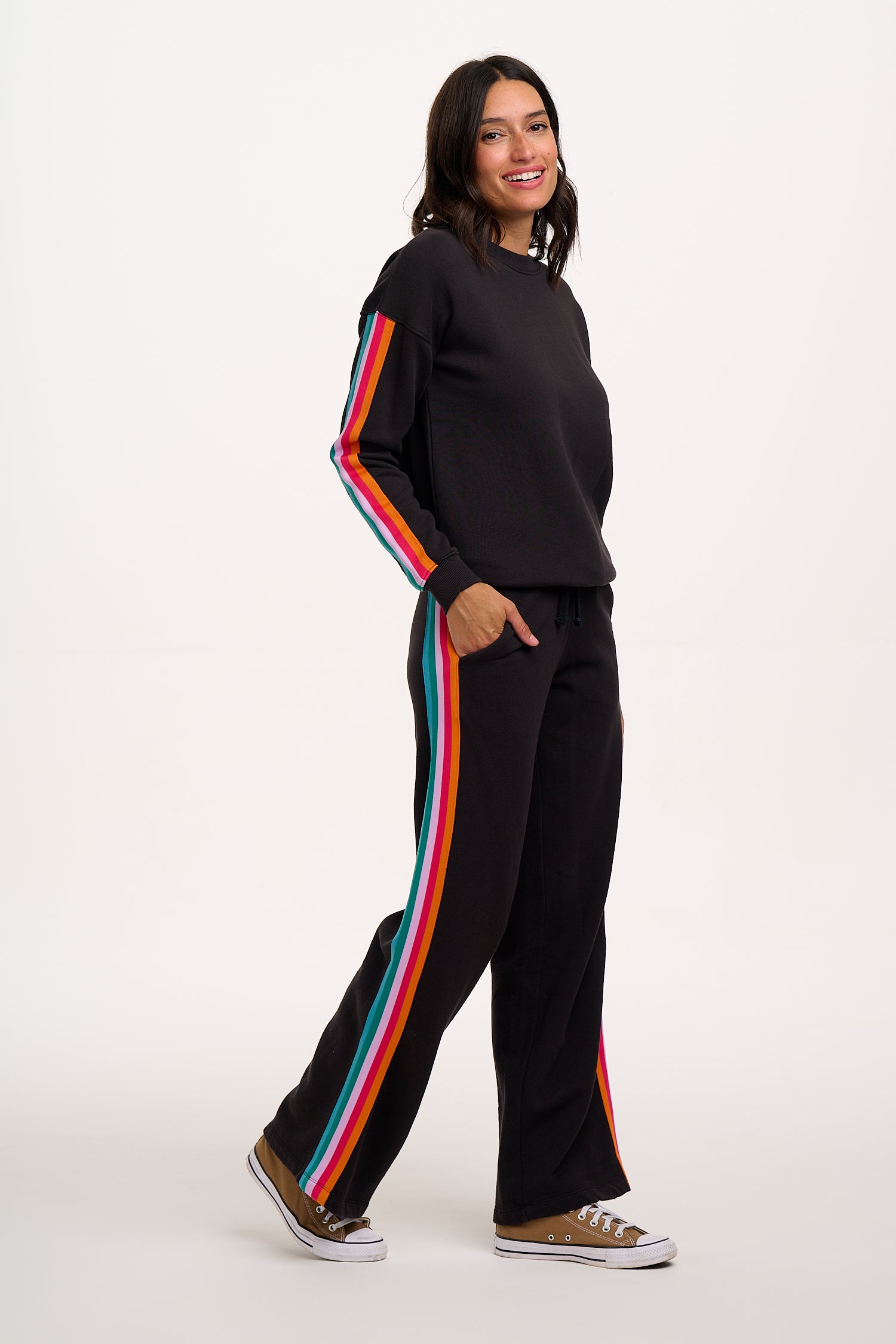 Woman wearing a black outfit with rainbow stripes on a white background