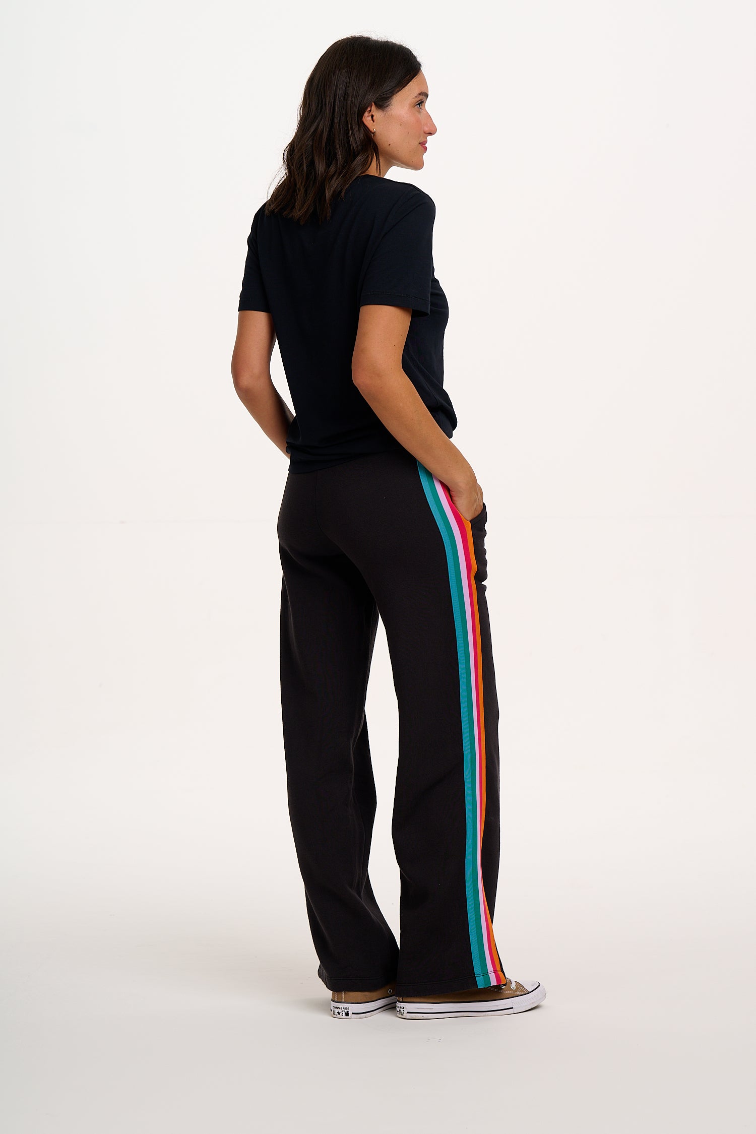 Person wearing black pants with colorful stripes on a white background