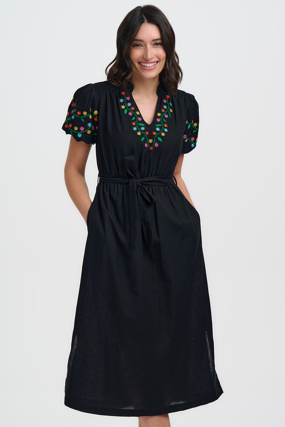 Woman wearing a black dress with colorful embroidery on a white background