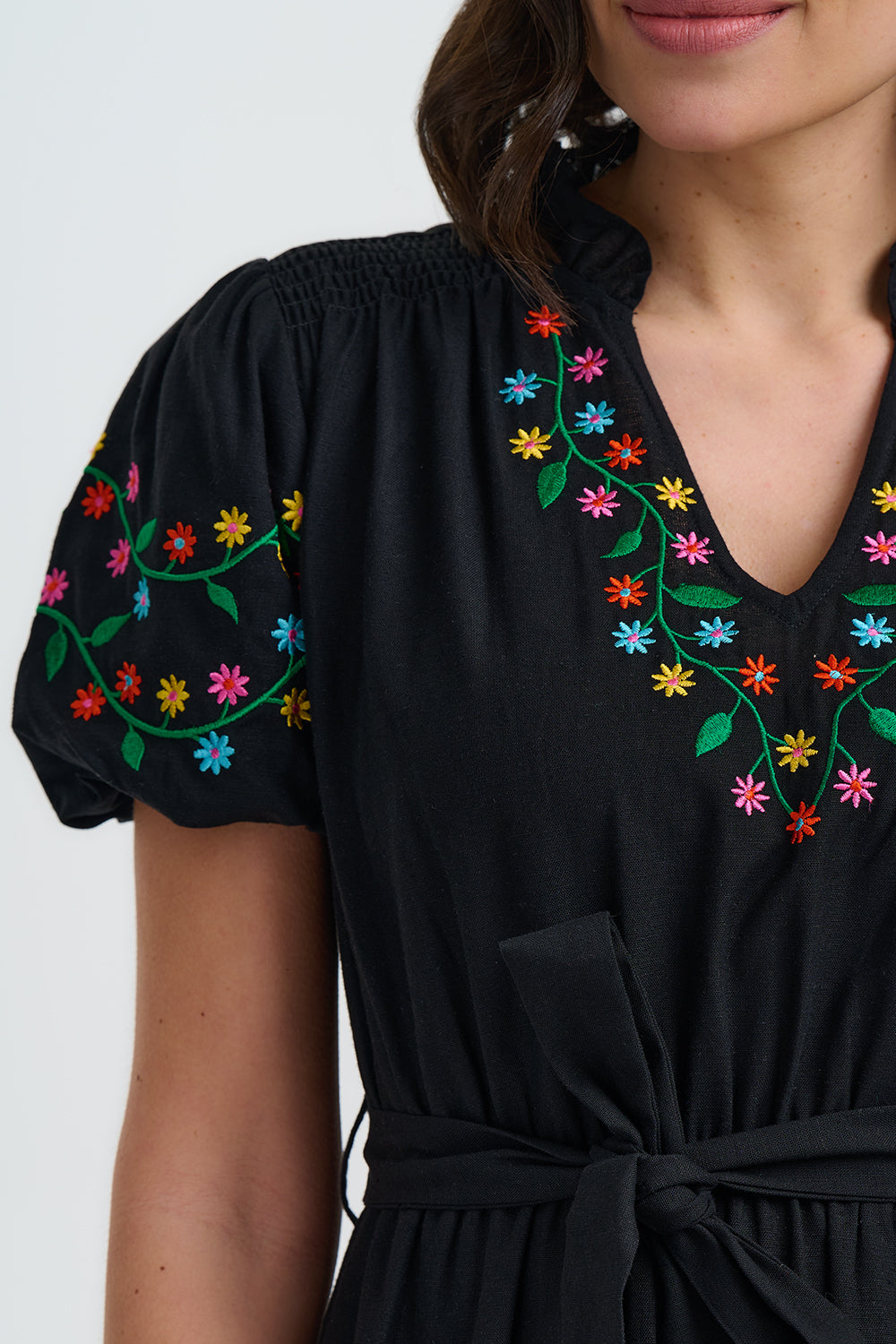 Black dress with colorful floral embroidery on a white background