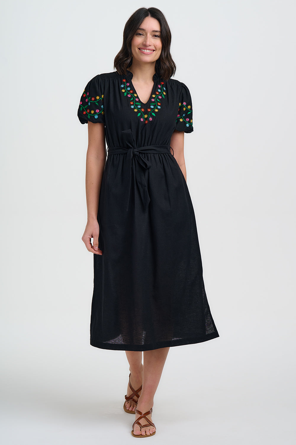 Woman wearing a black dress with colorful embroidery on a white background