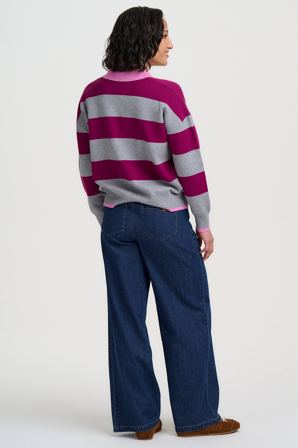 Person wearing a striped sweater and blue jeans on a white background