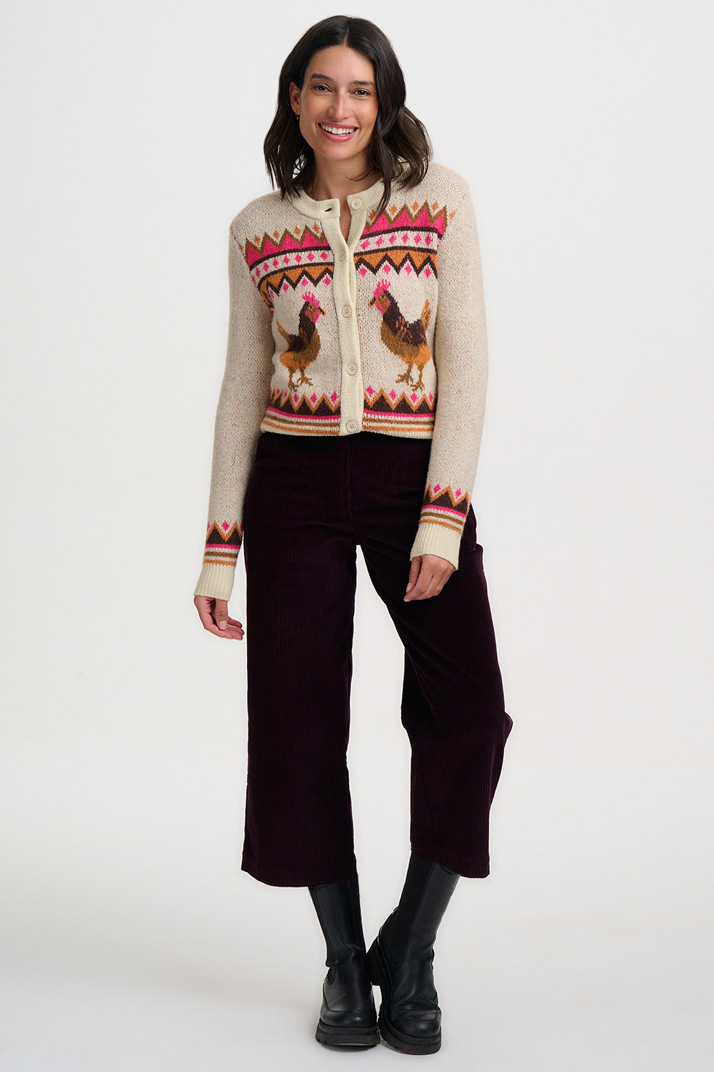 Woman wearing a patterned sweater with rooster design on a white background