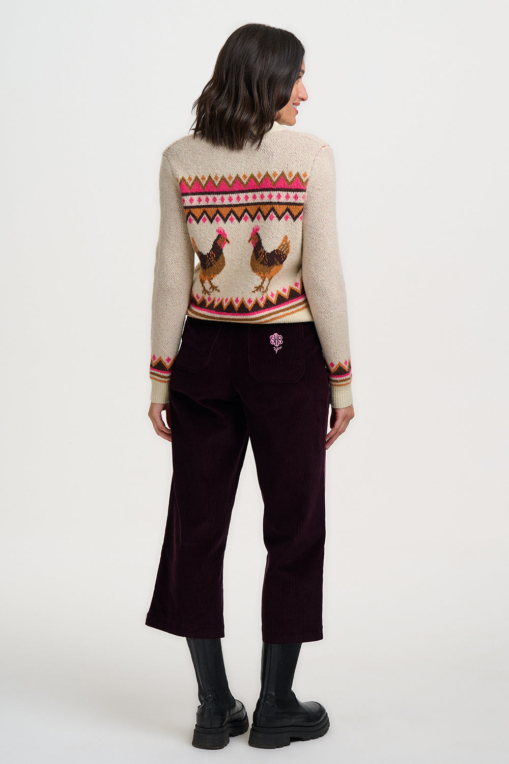 Person wearing a patterned sweater with rooster design on a white background