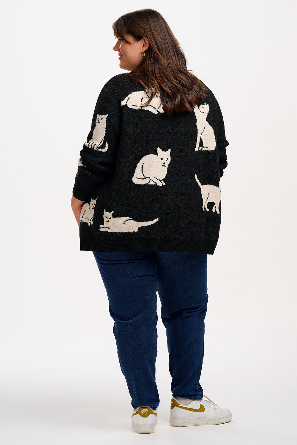 Woman wearing a black cardigan with cat patterns.