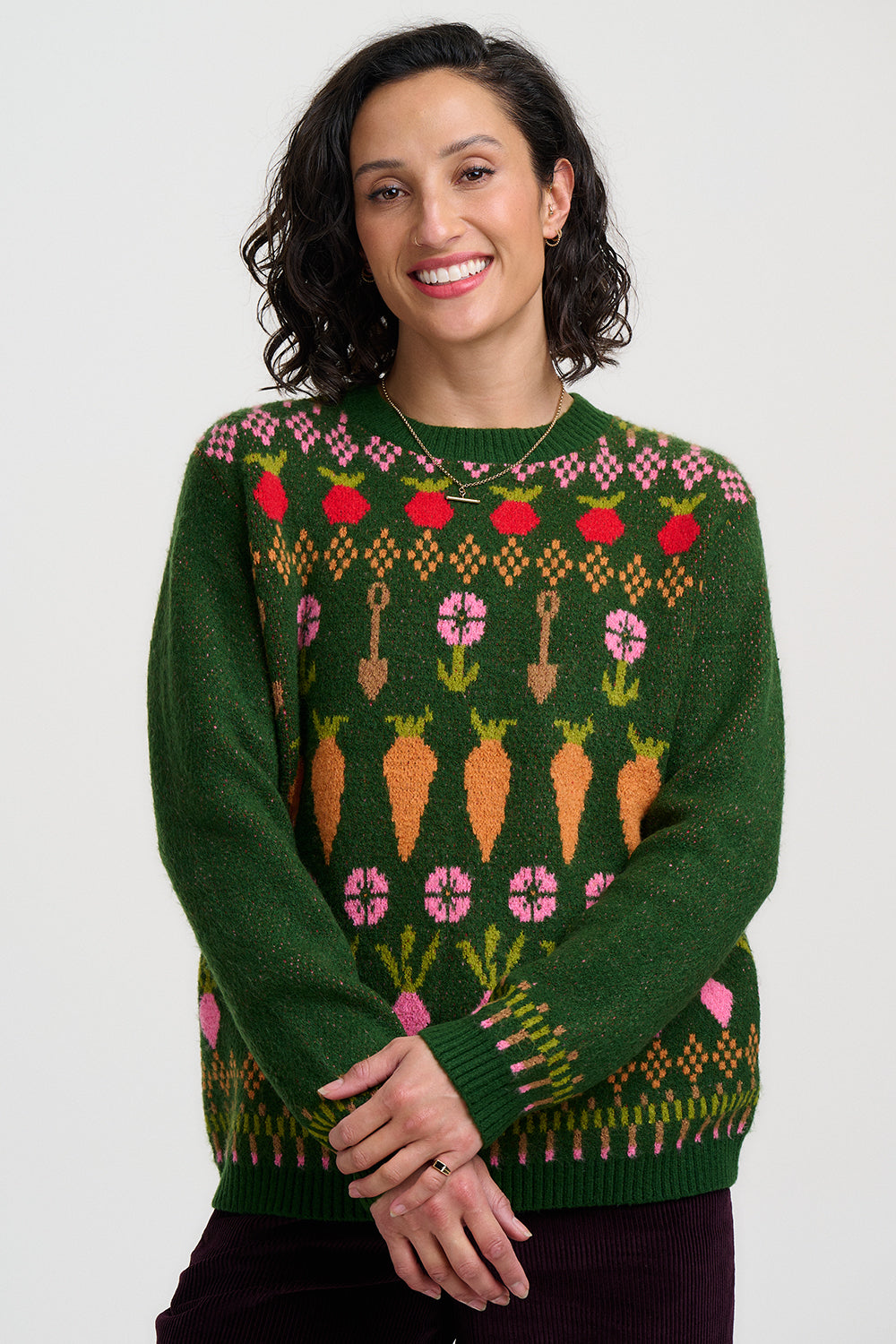 Woman wearing a green sweater with colorful pattern on a white background