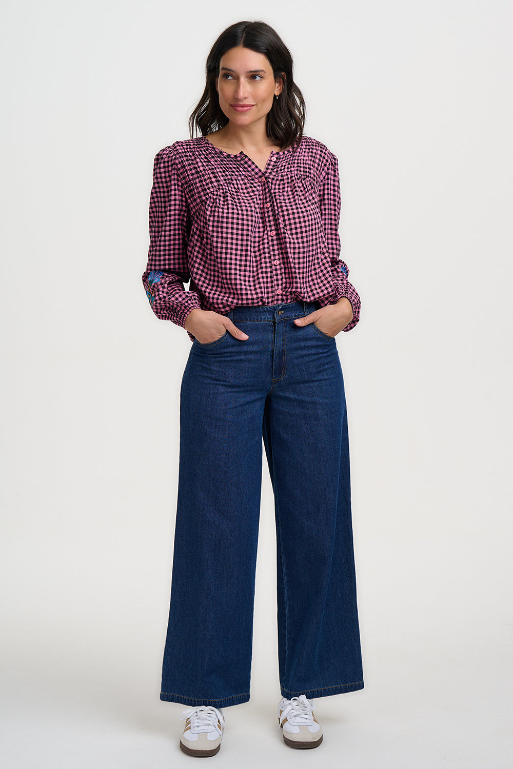 Woman wearing a red and white checkered shirt with blue jeans on a white background
