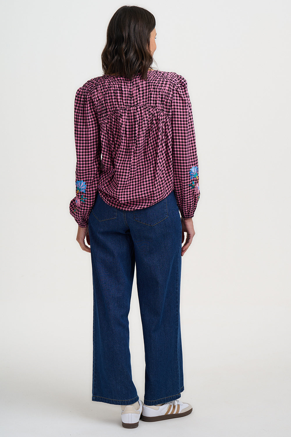 Person wearing a red and white checkered shirt with blue jeans on a white background