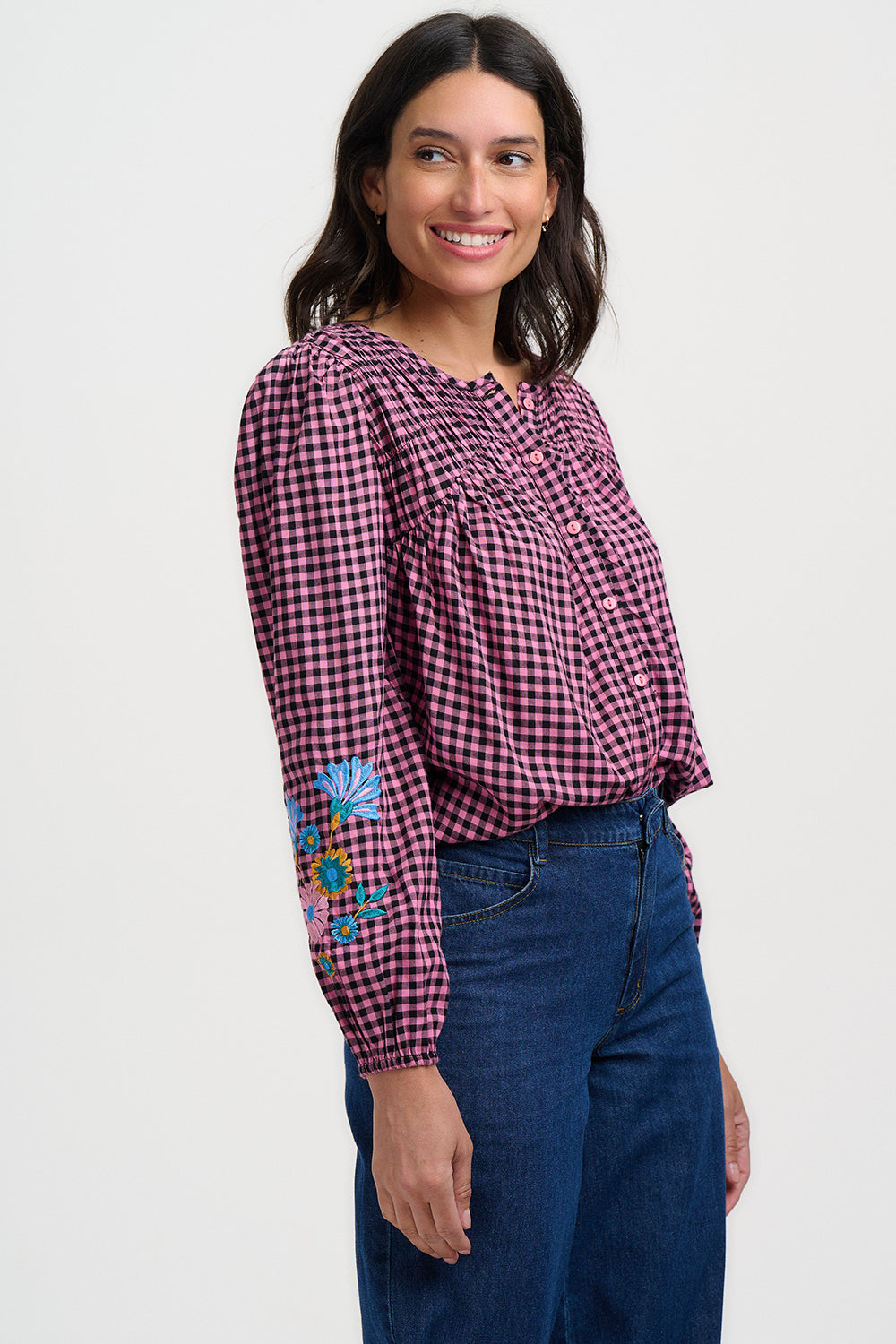 Woman wearing a checkered blouse with floral embroidery on a white background