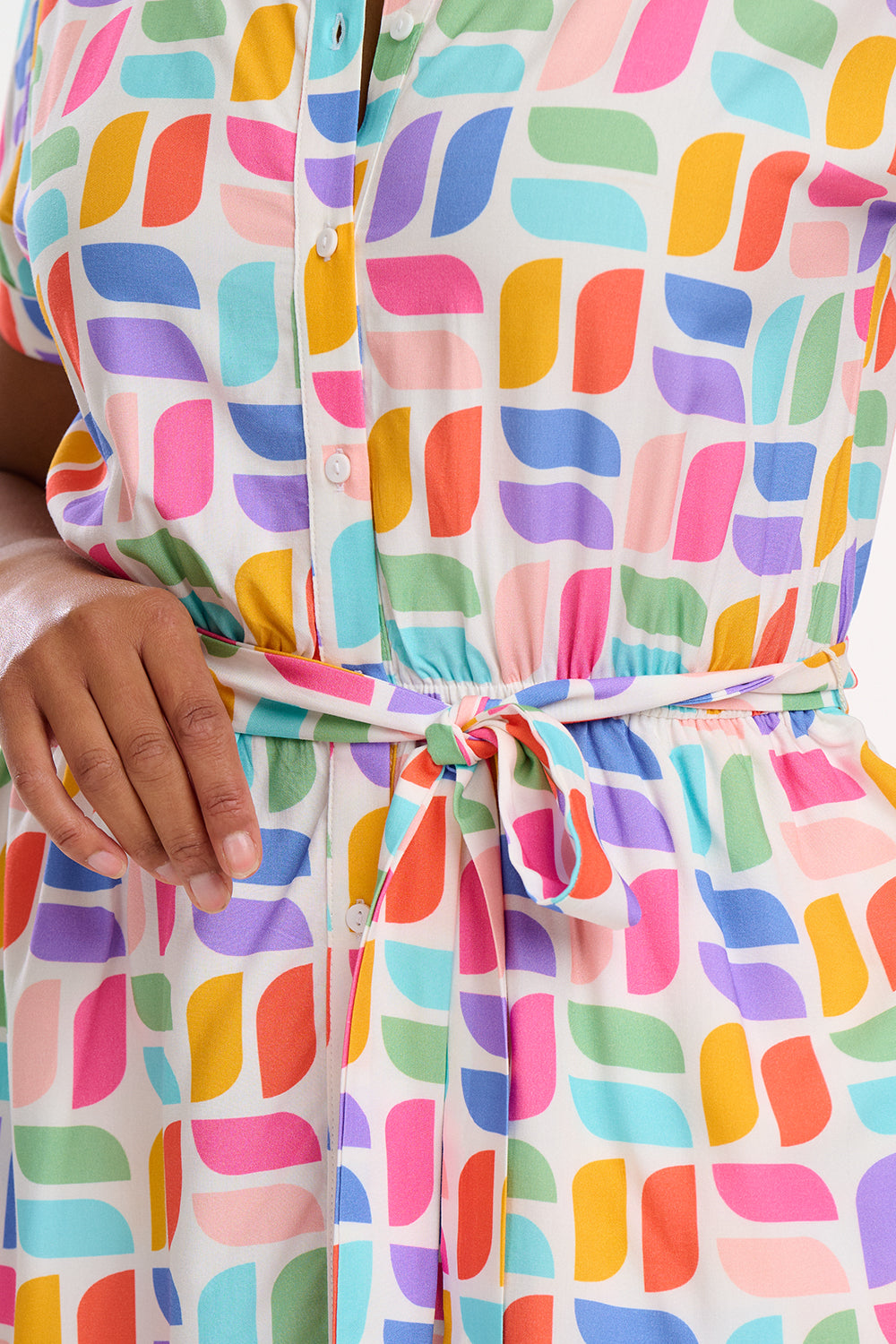 A model wearing an off-white midi shirt dress with a curved geometric print, featuring a traditional shirt collar, button placket, and elasticated waist.