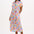 A model wearing an off-white midi shirt dress with a curved geometric print, featuring a traditional shirt collar, button placket, and elasticated waist.
