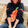 Person wearing a navy sweater with an orange design, sitting on a beige couch.