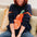 Person wearing a navy sweater with an orange design, sitting on a beige couch.
