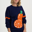 Woman wearing a navy sweater with an orange and green graphic design on a white background