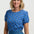 Woman wearing a blue floral top and denim skirt on a white background