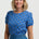Woman wearing a blue floral top and denim skirt on a white background