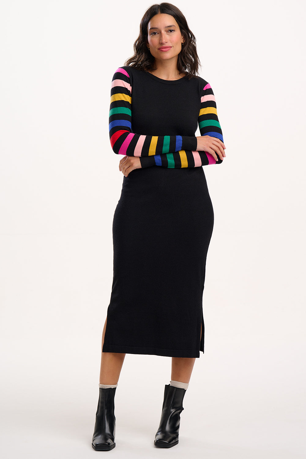Woman wearing a black dress with rainbow striped sleeves on a white background