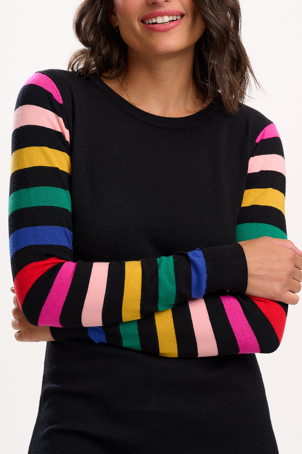 Black sweater with colorful striped sleeves worn by a person on a white background
