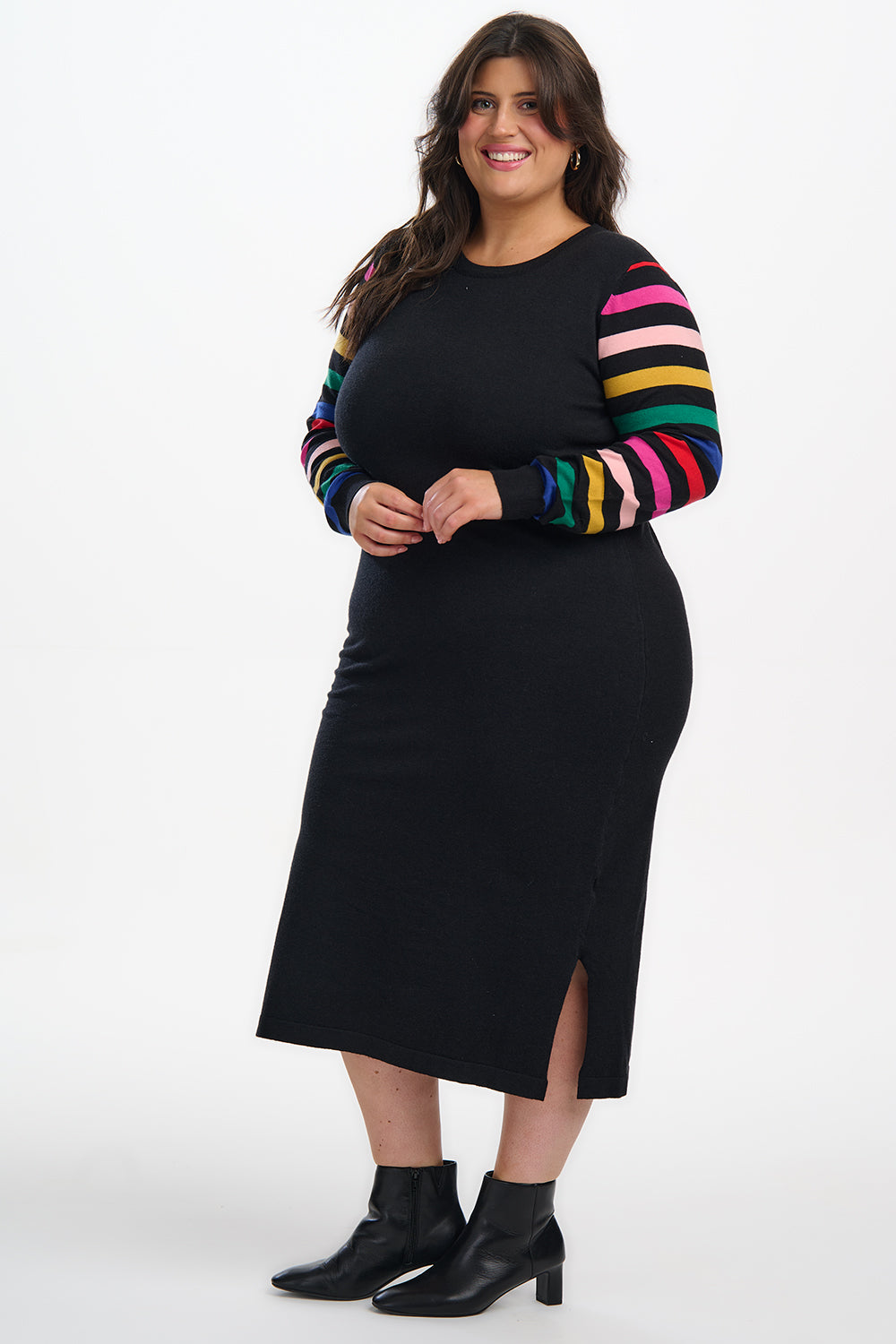 Woman wearing a black dress with a colorful striped sweater on a white background