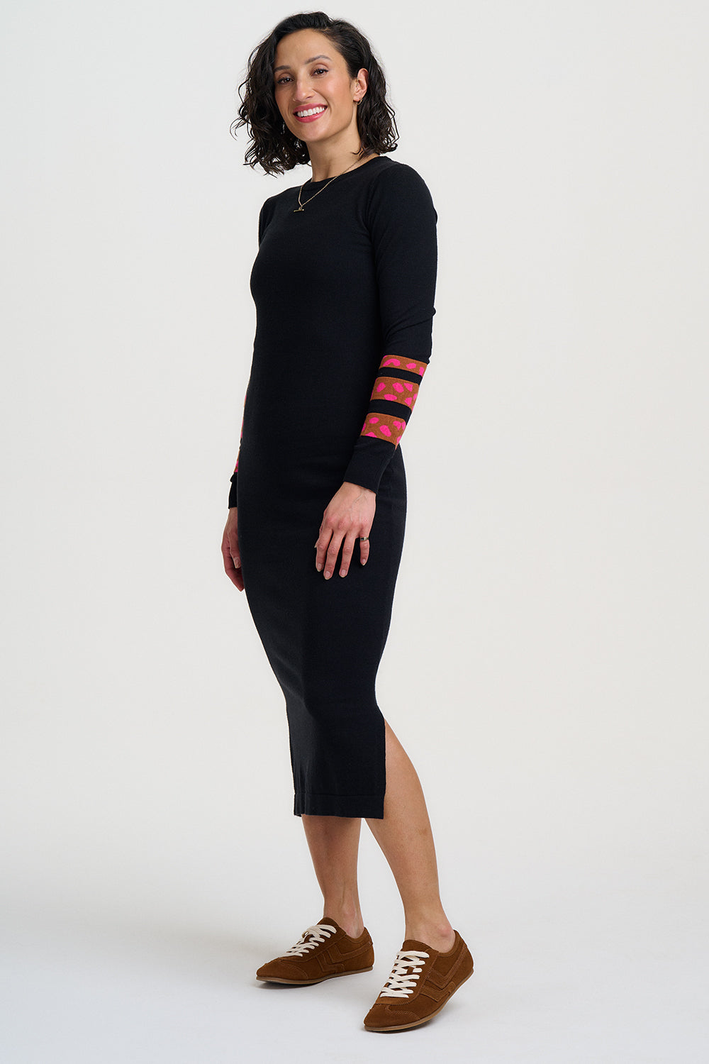 Woman wearing a black dress with red accents on sleeves against a white background