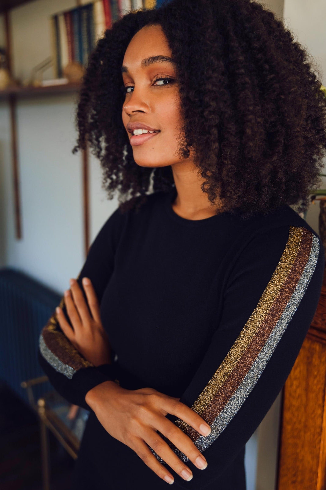 Woman wearing a black sweater with decorative sleeves in a room setting