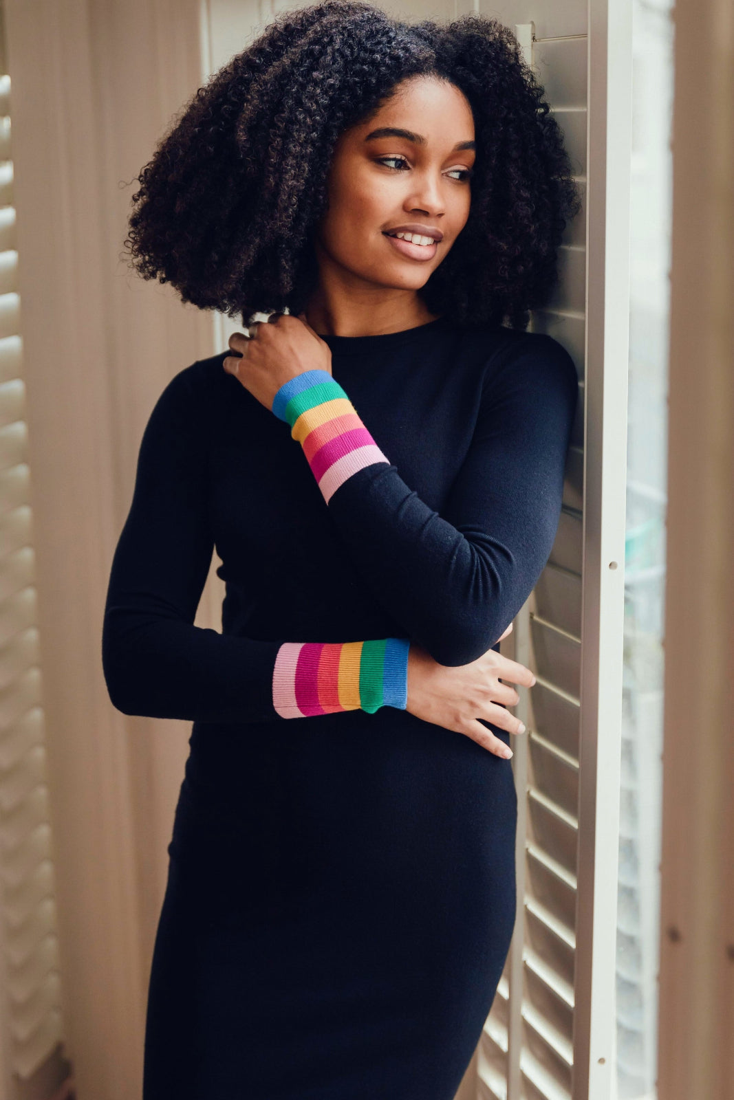 Woman wearing a black long-sleeve top with rainbow wristbands.