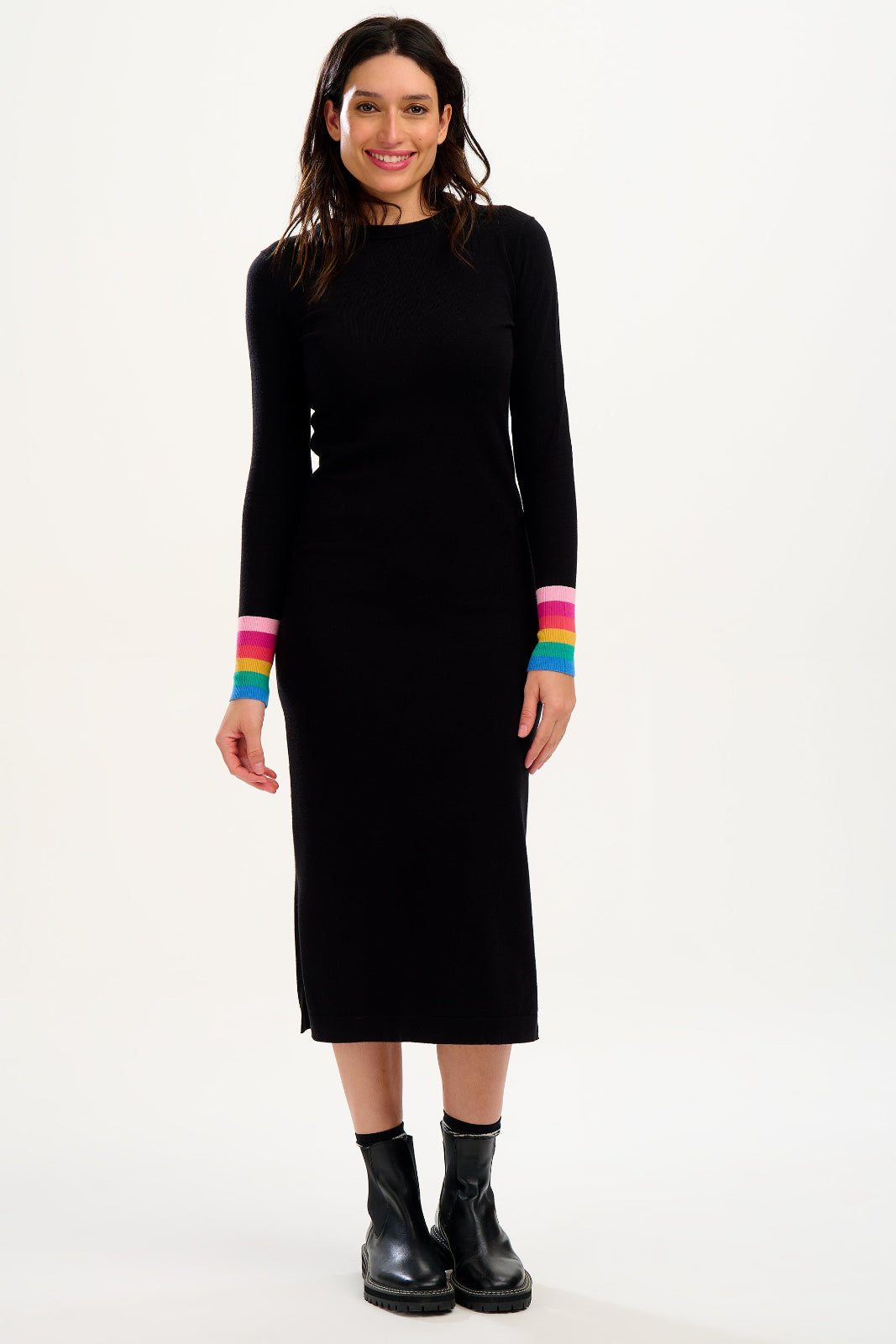 Woman wearing a black dress with rainbow-coloured cuffs on a white background
