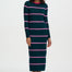 Woman wearing a long-sleeve, striped dress with pink and green colors on a white background
