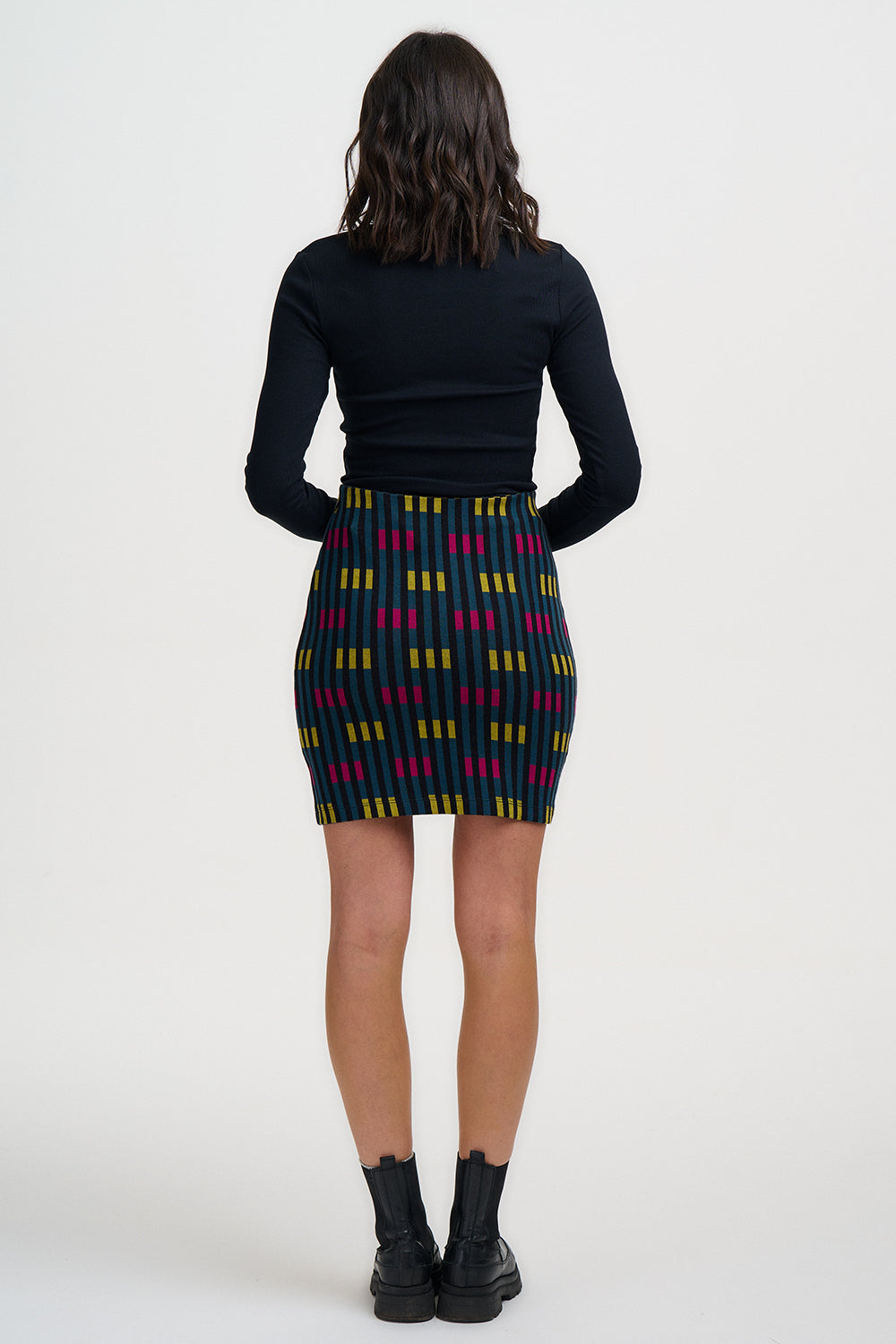 Person wearing a black top and patterned skirt on a white background