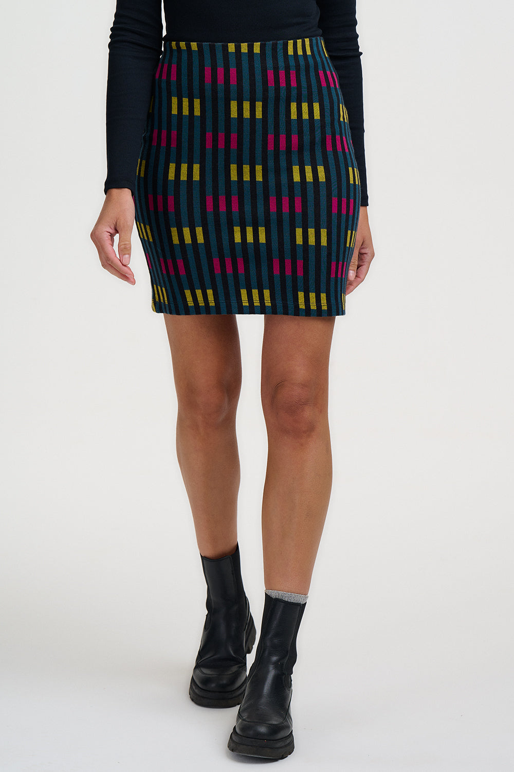 Person wearing a patterned skirt with black boots on a white background