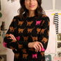 Woman wearing a black sweater with colorful cat pattern in a room with children's drawings on the wall.