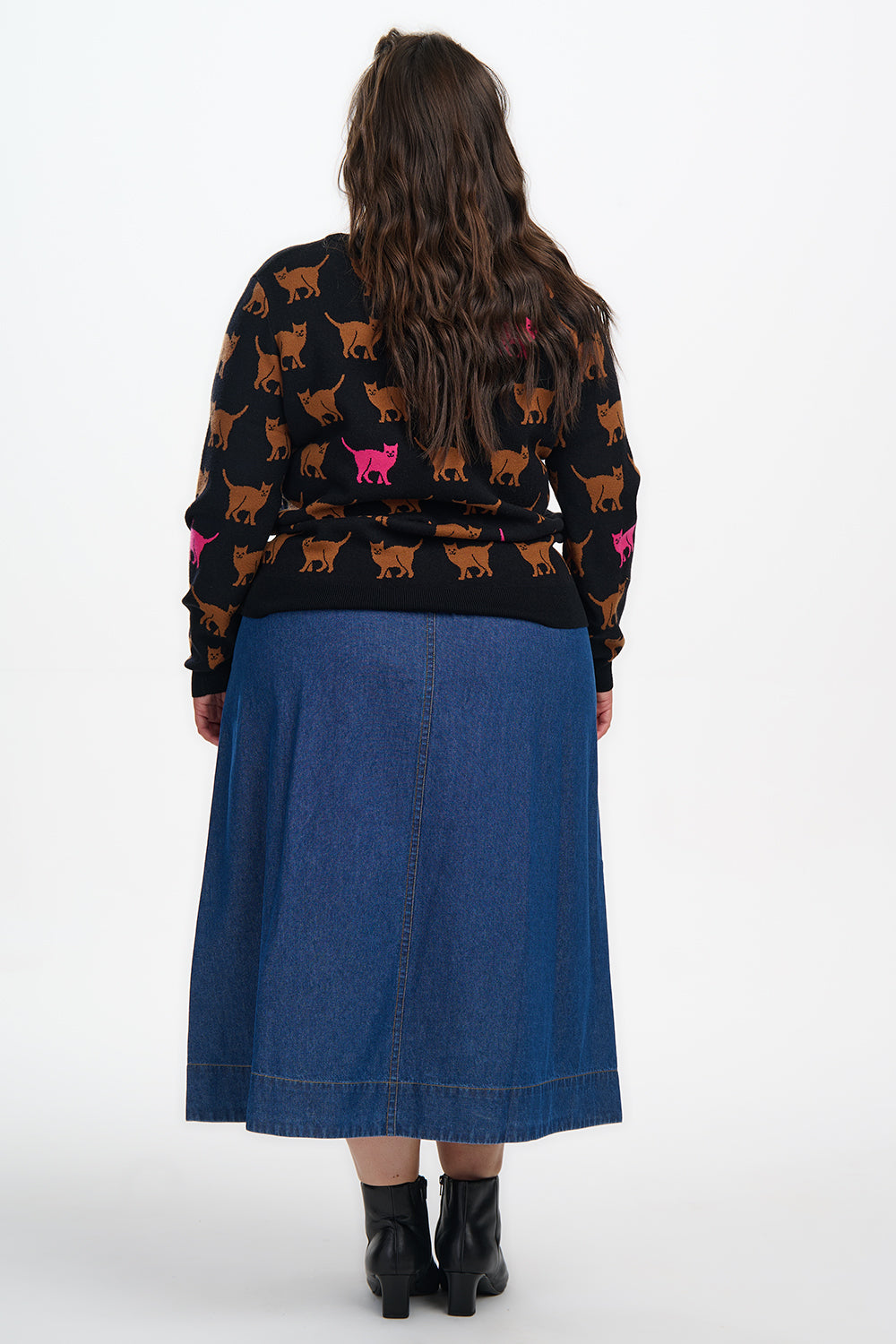 Person wearing a patterned sweater and blue skirt on a white background