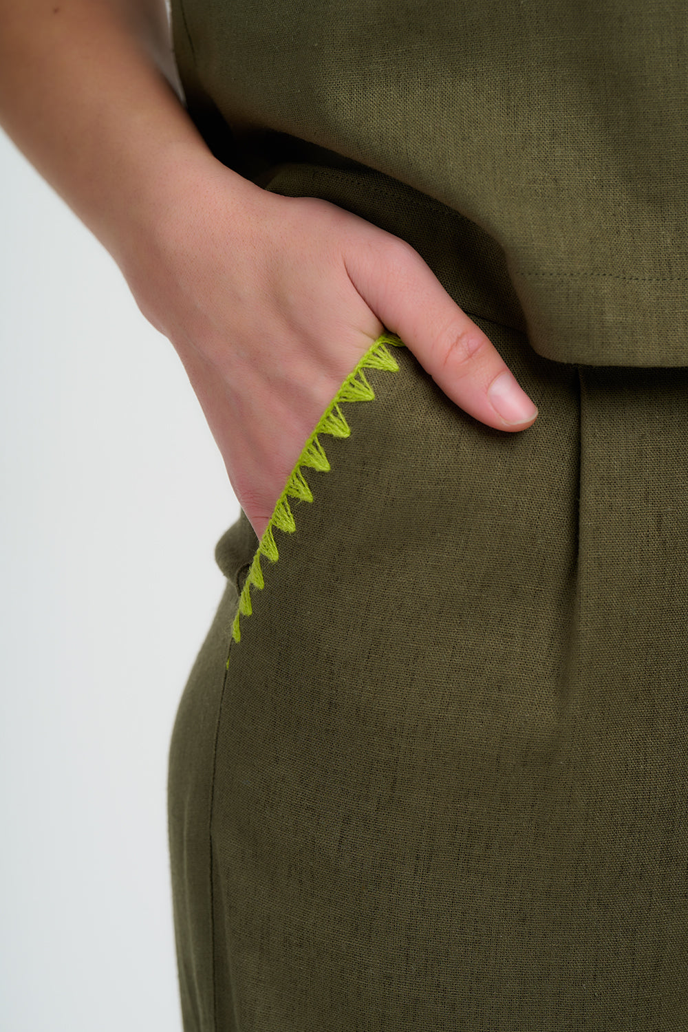 Green pants with a hand touching the fabric on a white background