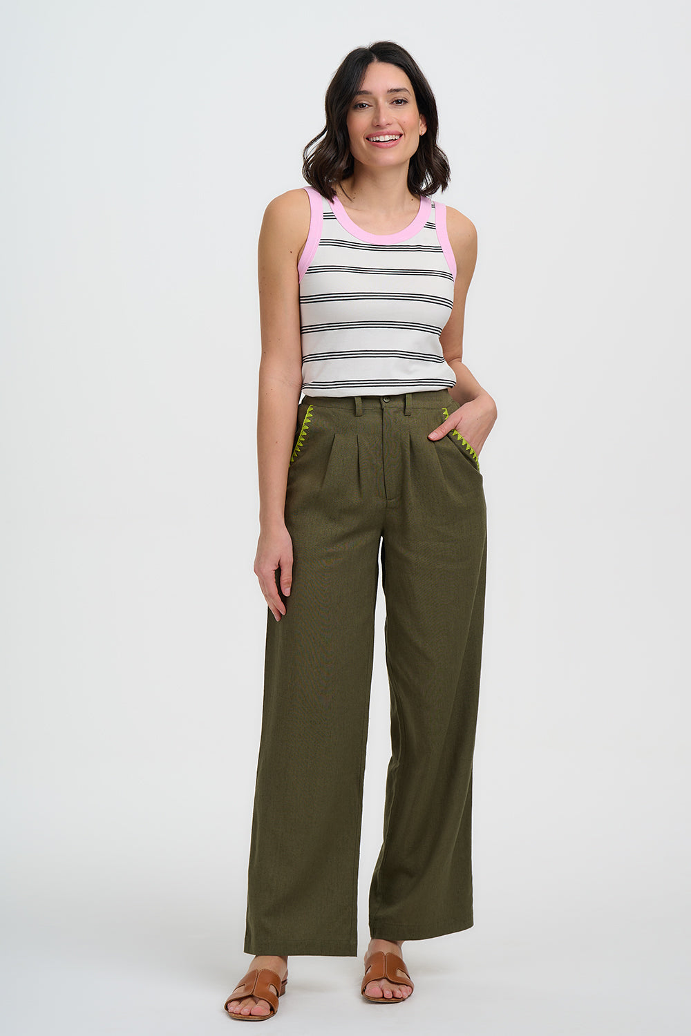 Woman wearing a striped tank top and olive green wide-leg pants on a white background