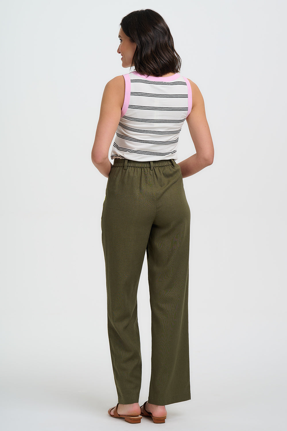 Woman wearing a striped sleeveless top and green pants on a white background
