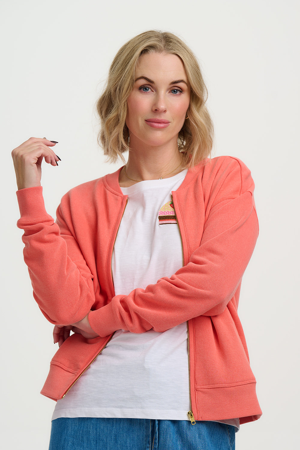Woman wearing a coral jacket over a white shirt on a plain background