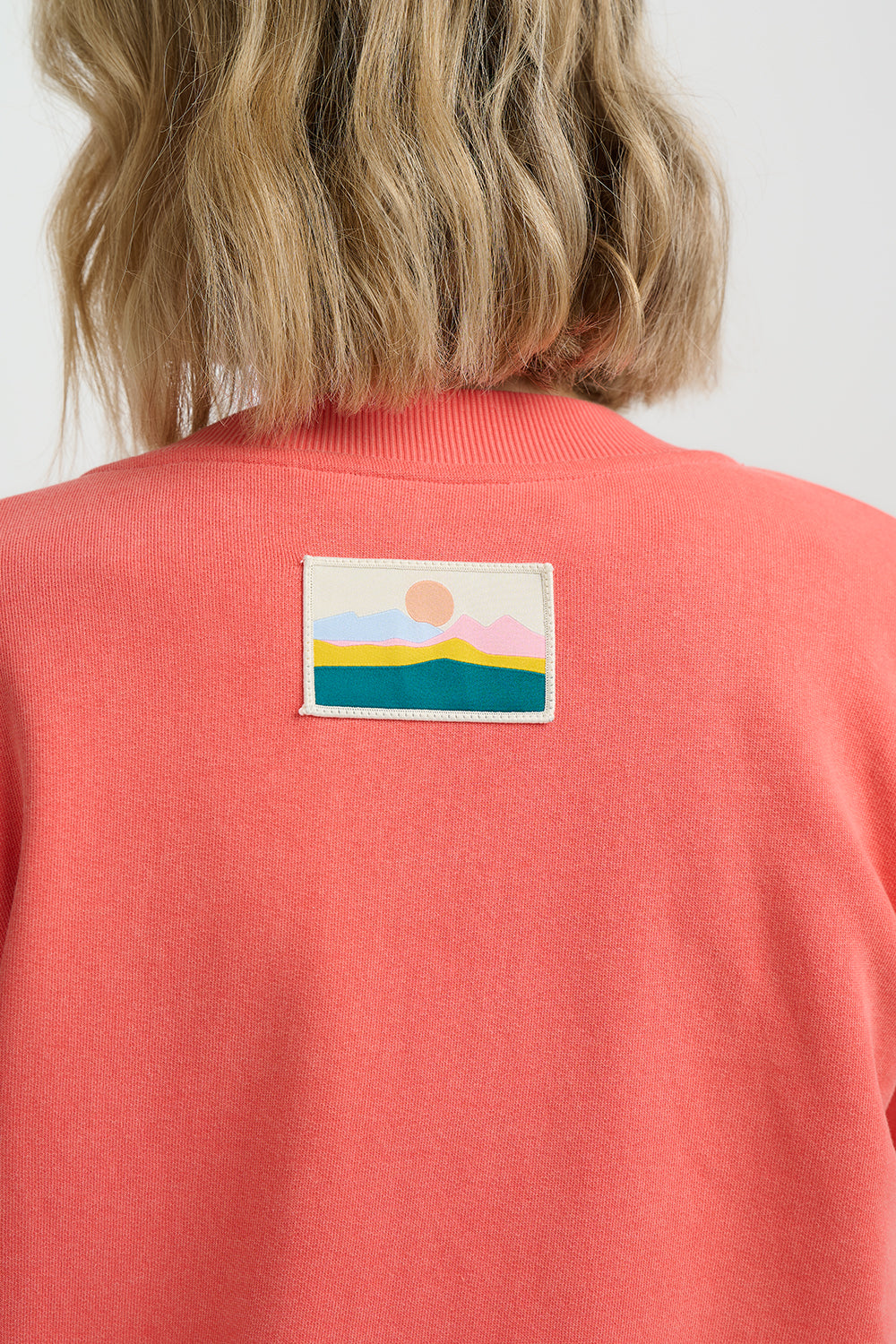 Person wearing a red sweater with a colorful patch on the back