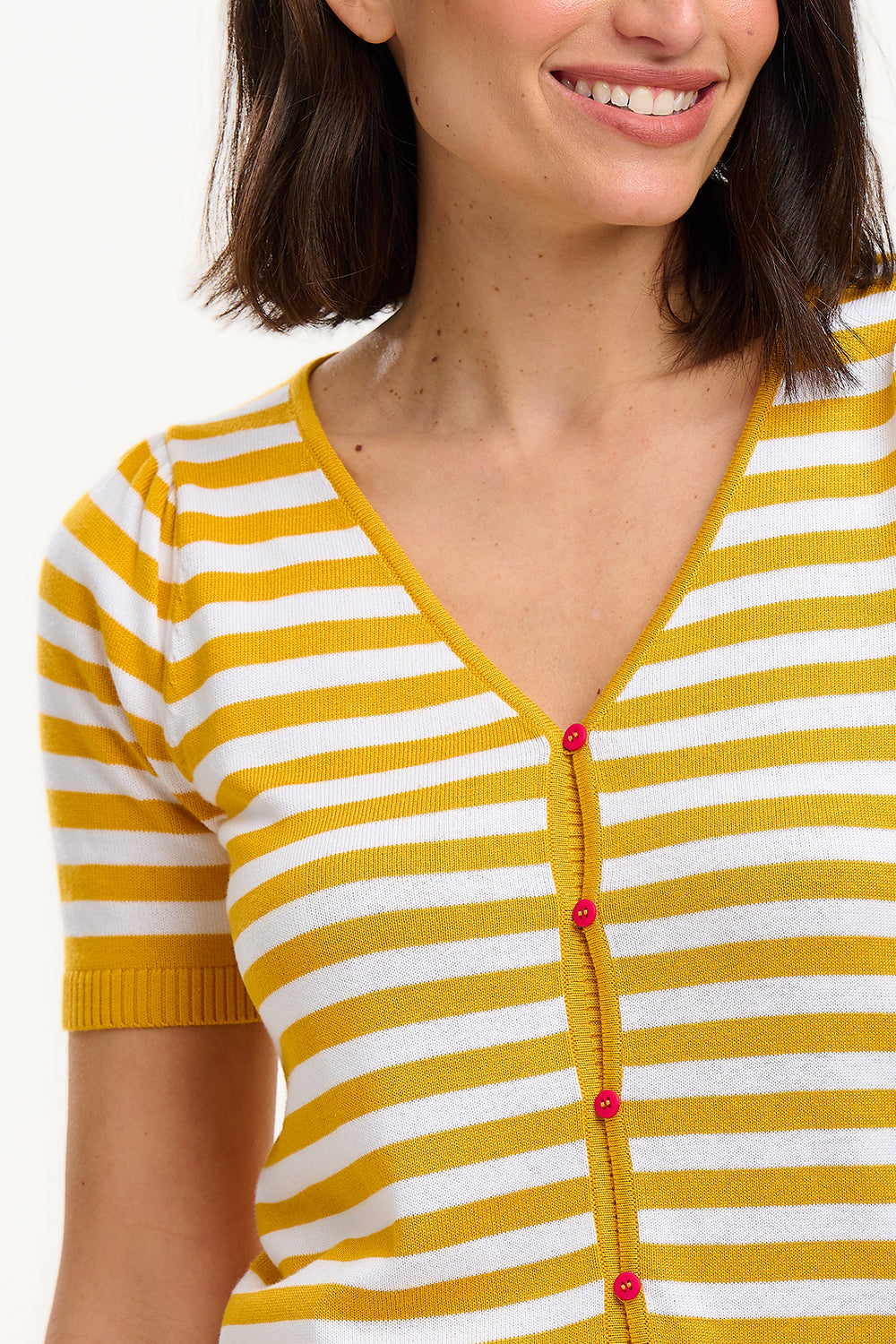 A woman modeling a striped yellow and off-white short-sleeved knit top with a V-neck and red buttons.