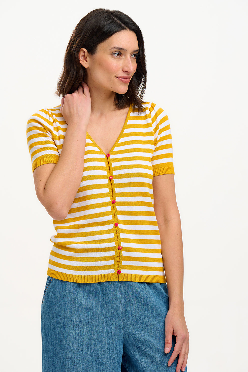 A woman modeling a striped yellow and off-white short-sleeved knit top with a V-neck and red buttons.