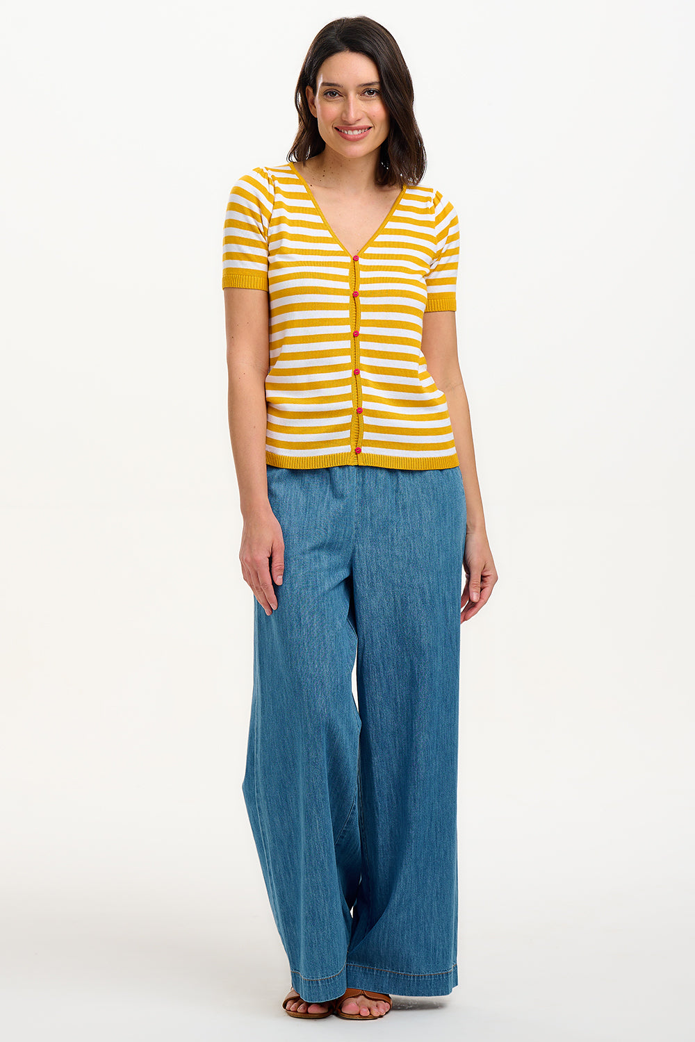 A woman modeling a striped yellow and off-white short-sleeved knit top with a V-neck and red buttons.