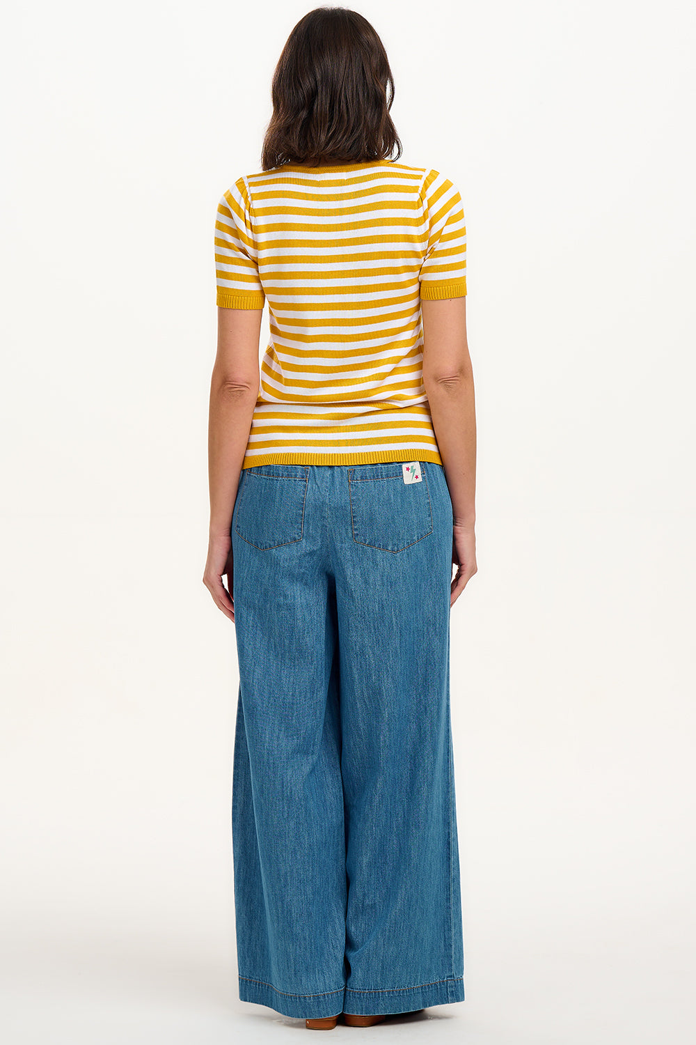 A woman modeling a striped yellow and off-white short-sleeved knit top with a V-neck and red buttons.