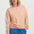 Woman wearing a pink and yellow striped sweater with blue jeans on a white background