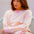 Woman wearing a pink and yellow striped sweater with blue jeans on a white background