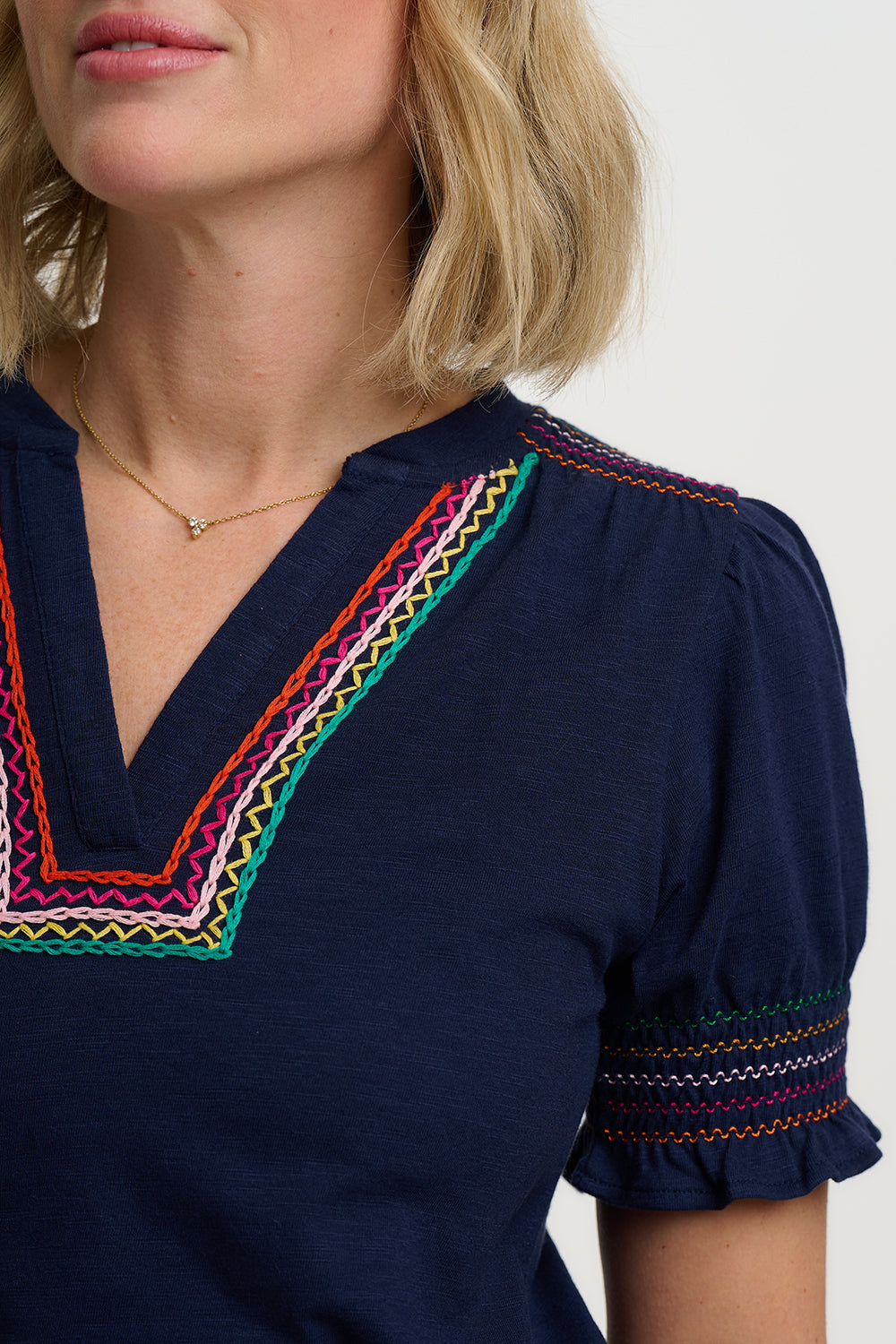 Navy blue top with colorful embroidery on neckline and sleeves against a white background