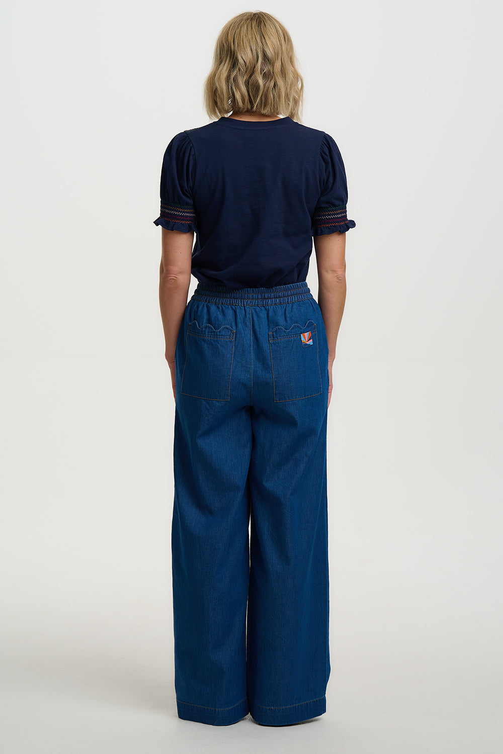 Person wearing a navy blue t-shirt and wide-leg pants on a white background