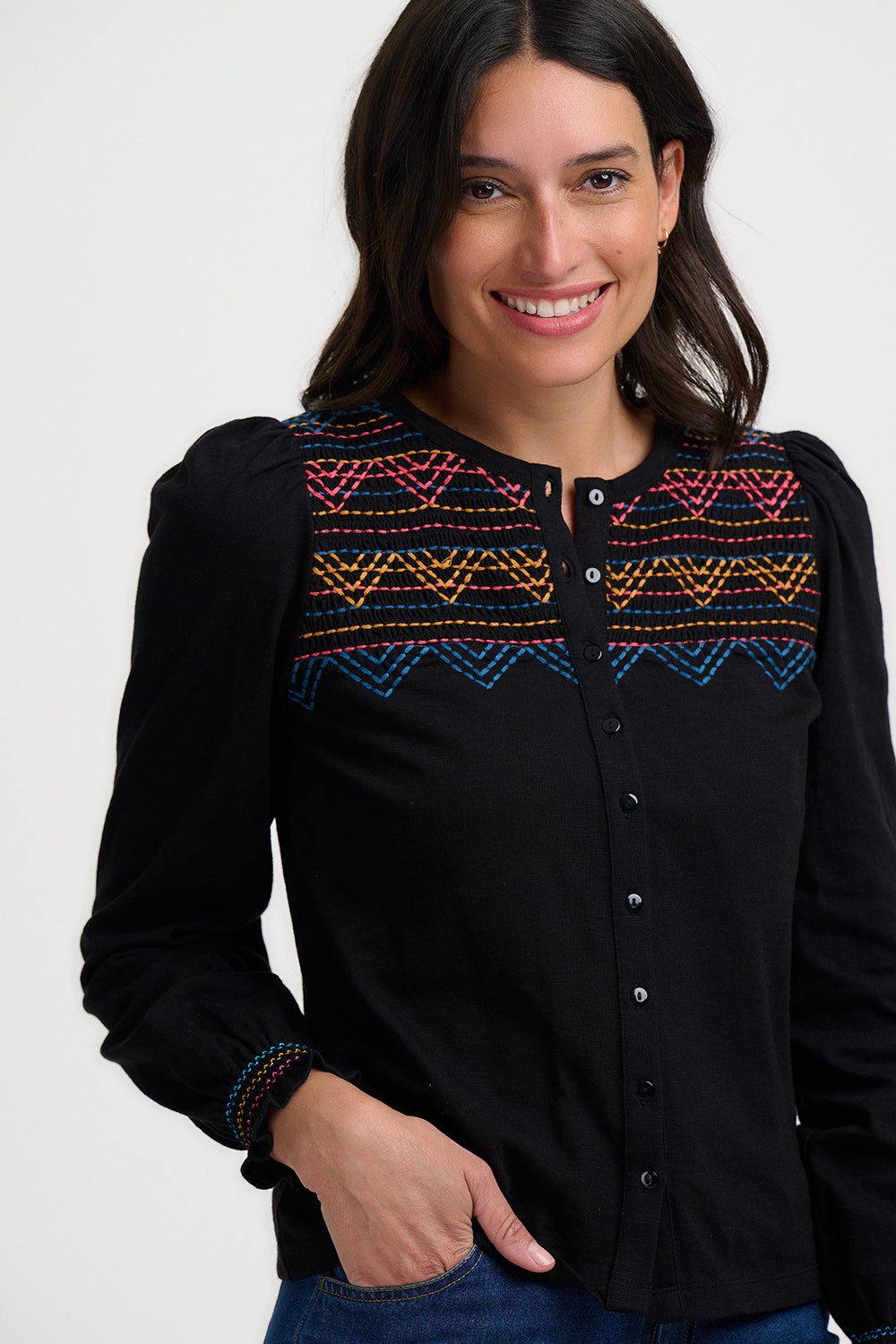 Woman wearing a black blouse with colorful embroidery on a white background
