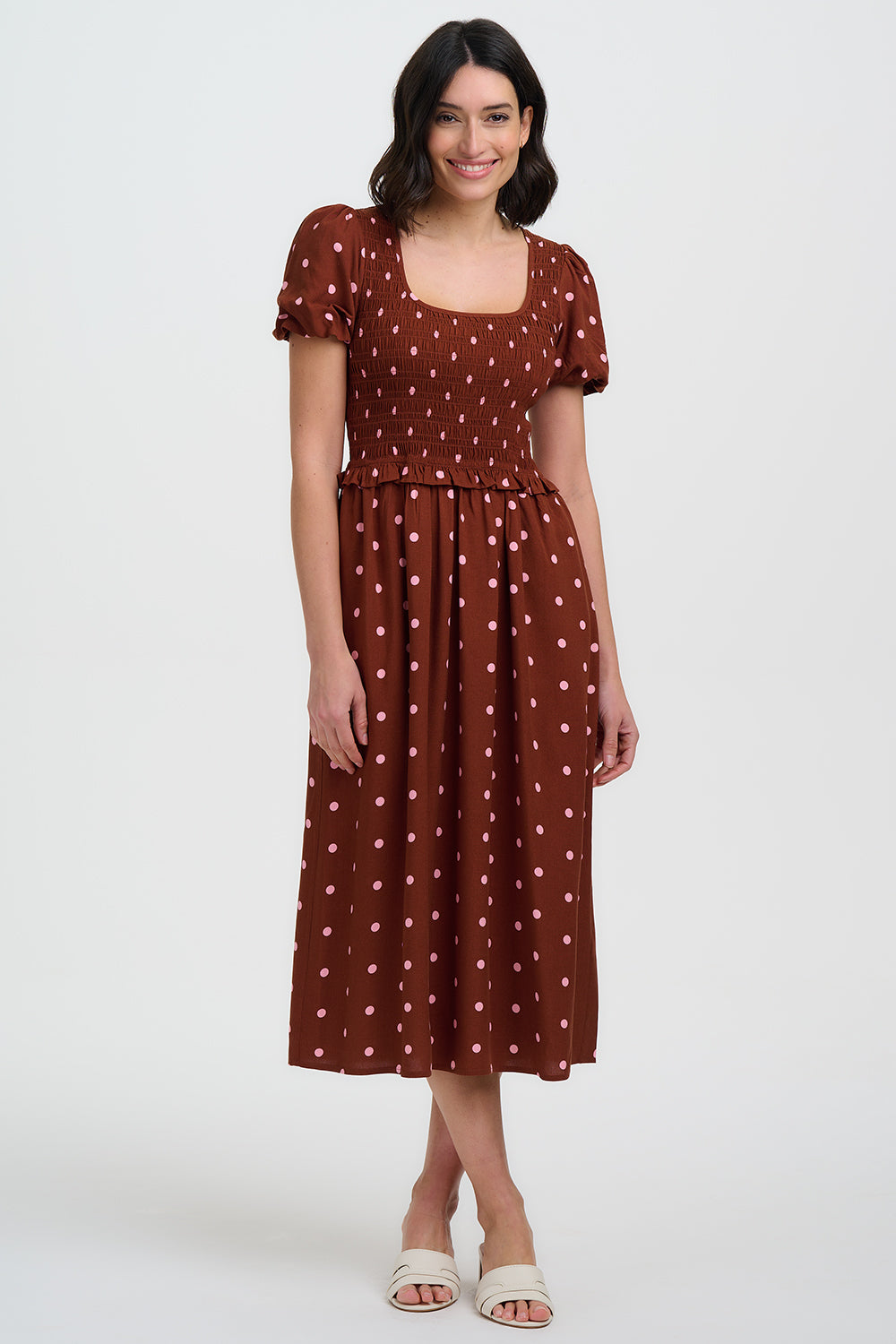 Woman wearing a brown polka dot dress on a white background