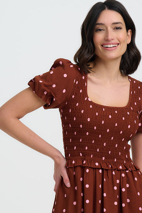 Woman wearing a brown dress with white polka dots on a white background