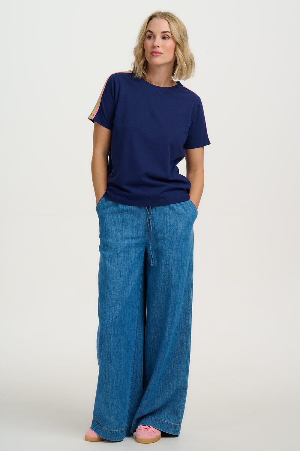 Woman wearing a navy blue t-shirt and wide-leg jeans on a white background