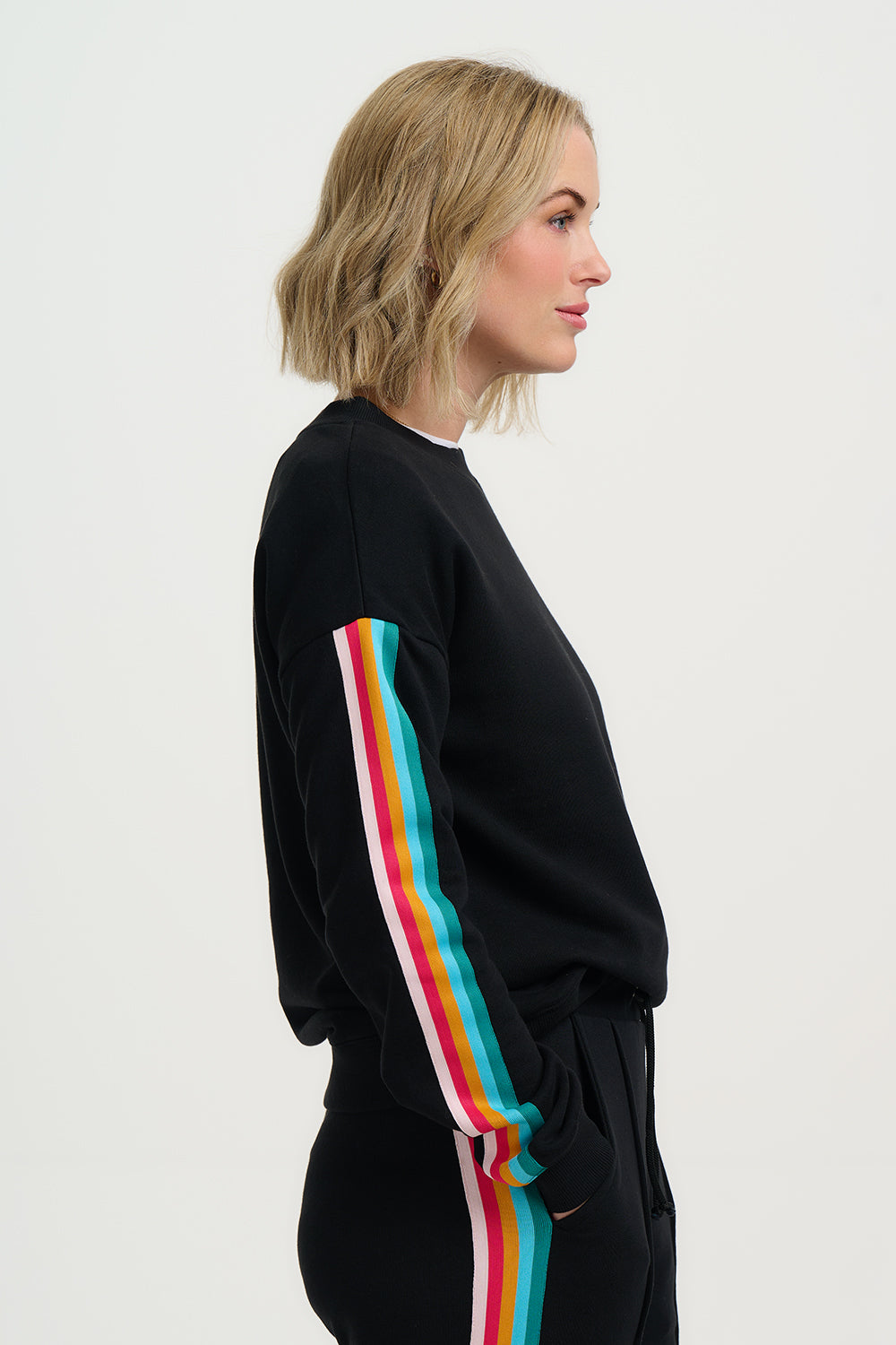 Woman wearing a black tracksuit with colorful stripes on a white background